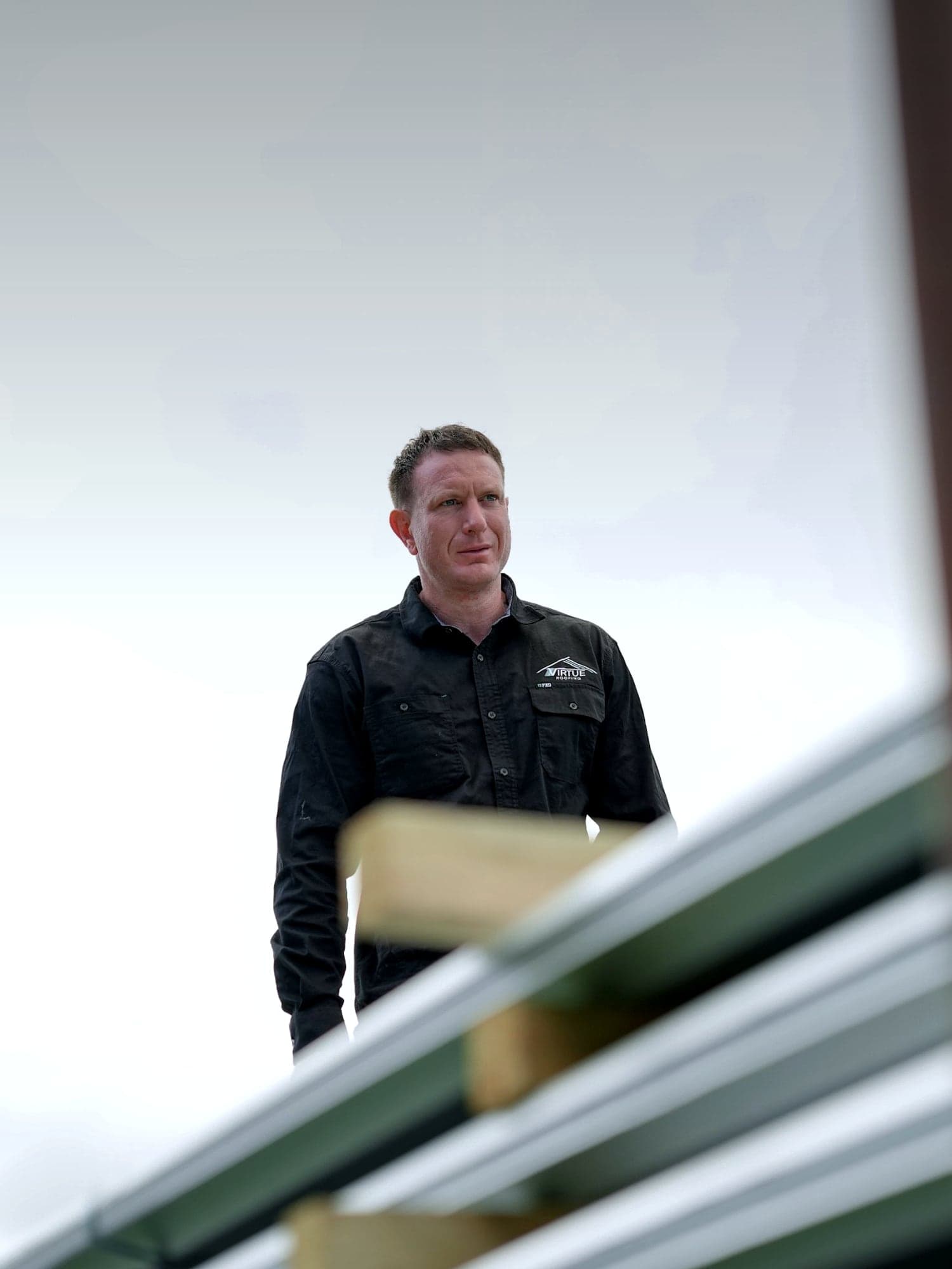 Dylan Lloyd, director of Virtue Roofing, standing on a roof under construction