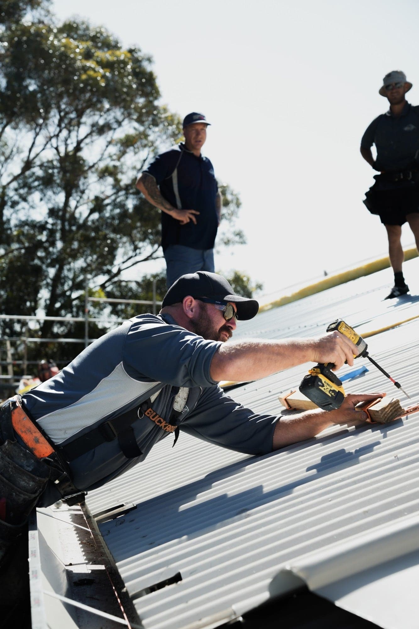 Virtue Roofing crew drilling off metal roof sheets at Prendiville College